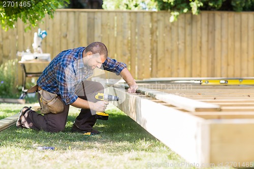 Image of Carpenter Drilling Wood At Construction Site