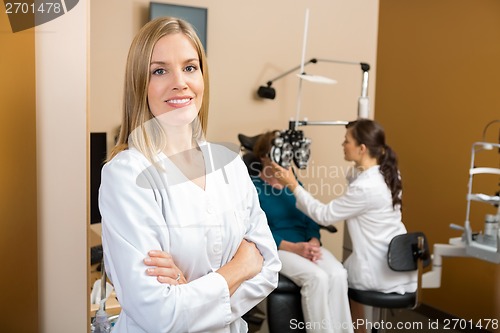 Image of Confident Eye Doctor With Colleague Examining Patient