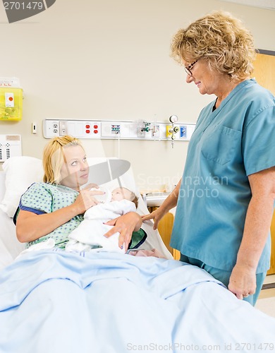 Image of Female Nurse Looking At Patient Feeding Milk To Babygirl