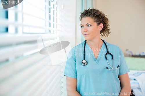 Image of Thoughtful Nurse Looking Out Through Window