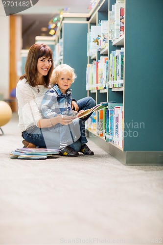 Image of Happy Teacher And Boy Reading Book In Library