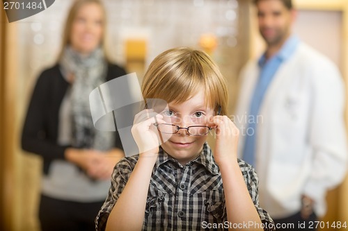 Image of Boy Trying Eyeglasses With Optometrist And Mother At Store