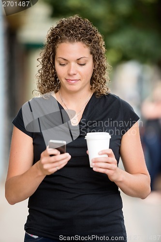 Image of Woman With Coffee Cup Messaging On Smartphone