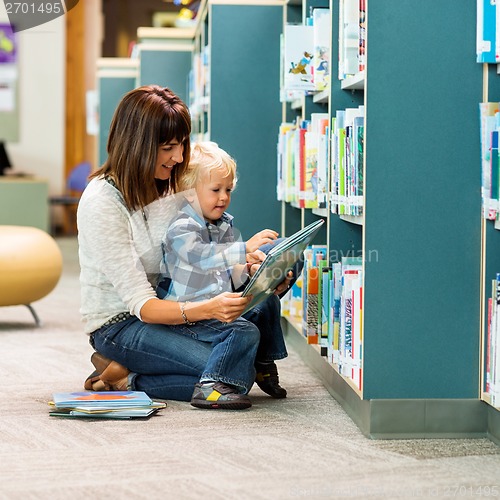 Image of Teacher And Schoolboy Reading Book By Bookshelf