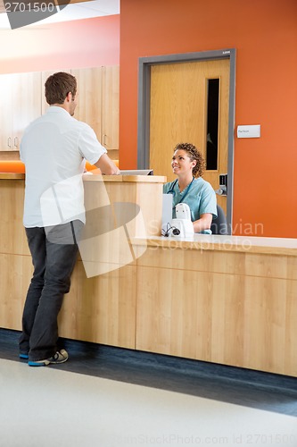Image of Patient Conversing With Nurse At Reception Desk