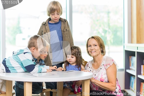 Image of Teacher With Students Using Tablet Computer In Library