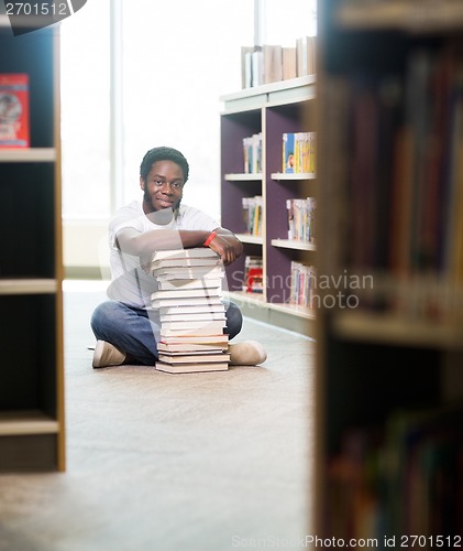 Image of Confident Student With Stacked Books Sitting In Library