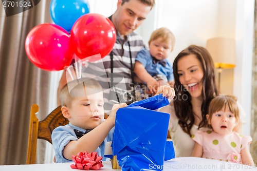 Image of Family Looking At Birthday Boy Opening Gift Box