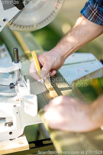 Image of Carpenter Marking On Wood Using Ruler At Table Saw