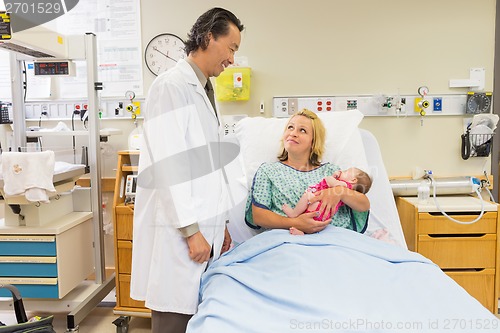 Image of Mother Holding Newborn Babygirl While Looking At Doctor