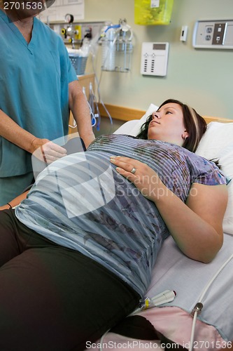 Image of Pregnant Woman Looking At Nurse Taking Her Blood Pressure