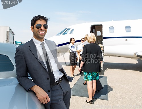 Image of Happy Businessman Leaning On Car At Airport Terminal