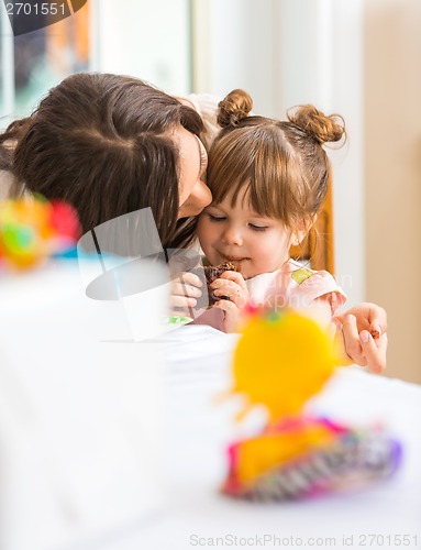 Image of Mother Kissing Girl Eating Cupcake