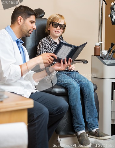 Image of Boy Smiling While Optometrist Holding Test Chart