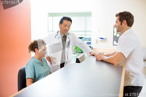 Image of Medical Team Working On Computer While Man Standing At Reception