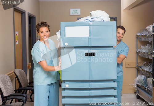 Image of Nurses Pushing Trolley Filled With Linen In Hospital Hallway