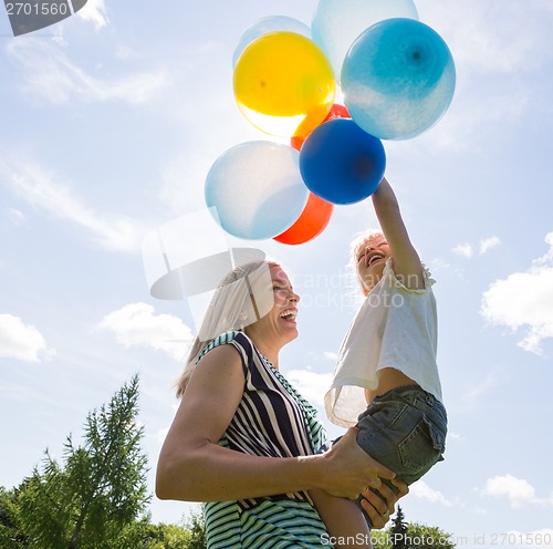 Image of Mother And Daughter Playing With Balloons Against Sky