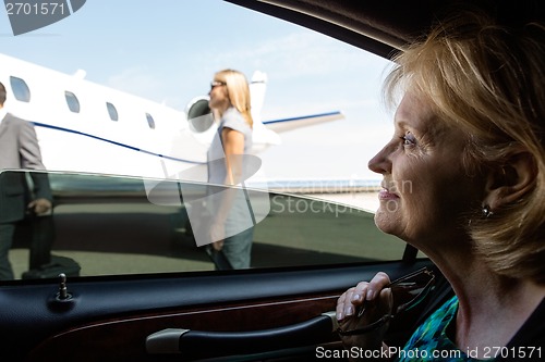 Image of Businesswoman In Car Looking At Private Jet