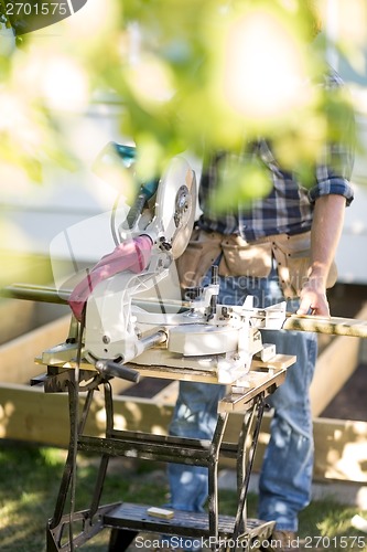 Image of Worker Holding Wooden Plank At Table Saw