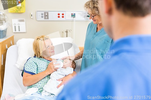 Image of Nurse Looking At Woman Feeding Milk To Babygirl In Hospital