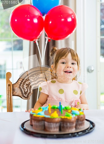 Image of Girl Sitting In Front Of Cake At Home