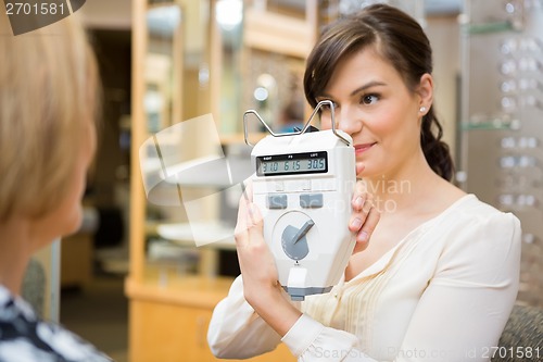 Image of Optometrist Showing Pupilometer To Mature Woman