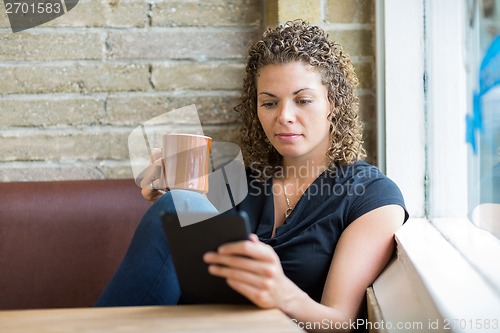 Image of Woman Using Digital Tablet While Having Coffee In Cafe