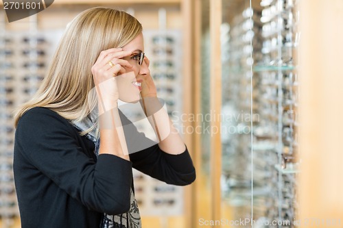 Image of Woman Trying On Eyeglasses In Store