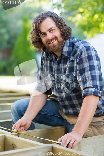 Image of Construction Worker Measuring Wood