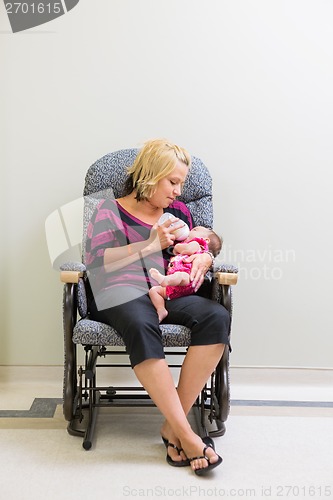 Image of Mother Feeding Milk To Newborn Baby Girl On Chair