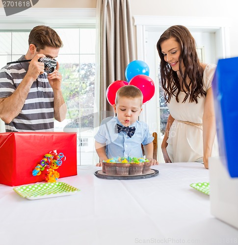 Image of Boy Blowing Out Candles On Cake At Home