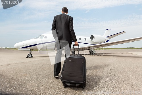 Image of Businessman Walking Towards Corporate Jet