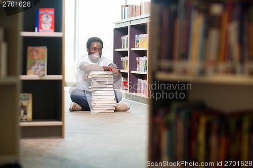 Image of Happy Student With Stacked Books Sitting In Library