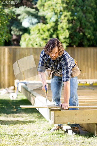 Image of Carpenter Cutting Wood With Saw At Construction Site