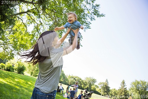 Image of Playful Young Mother Lifting Baby Boy At Park