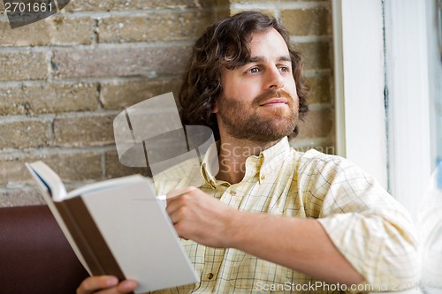 Image of Man With Book Looking Through Window In Coffeeshop