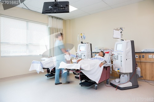 Image of Nurse Walking By Patient Receiving Renal Dialysis