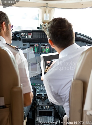 Image of Pilot And Copilot Using Digital Tablet In Cockpit