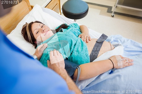 Image of Pregnant Woman Smiling While Being Consoled By Husband In Hospit