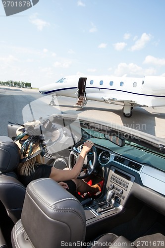 Image of Woman In Convertible With Private Jet At Terminal