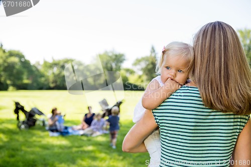 Image of Mother Carrying Daughter Looking Away In Park