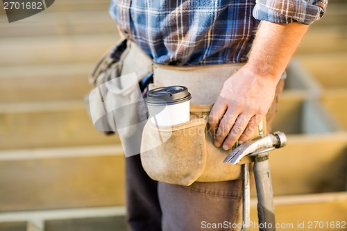 Image of Disposable Coffee Cup And Hammer On Carpenter's Tool Belt