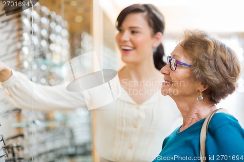 Image of Woman Assisting Senior Customer In Selecting Glasses