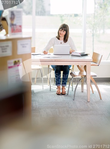 Image of Student Writing Notes In Library