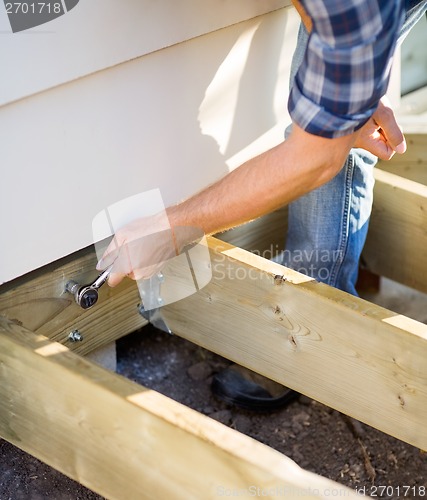 Image of Carpenter's Hand Tightening Bolt With Wrench