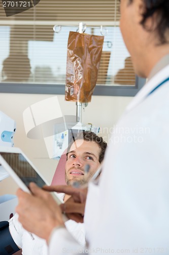 Image of Patient Looking At Doctor Holding Digital Tablet In Chemo Room