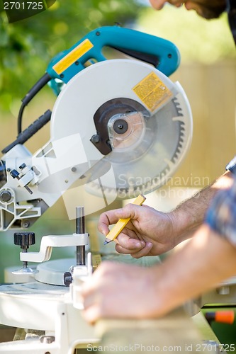 Image of Carpenter's Hands Marking On Wood At Table Saw