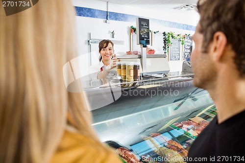 Image of Saleswoman Looking At Customers In Butcher's Shop