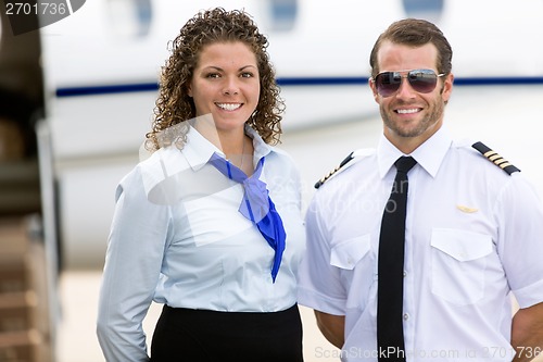 Image of Stewardess And Pilot Standing Against Private Jet