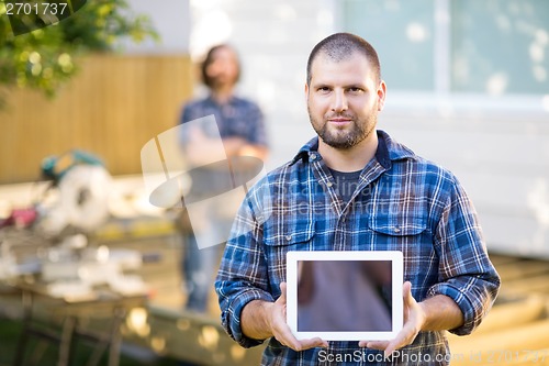 Image of Confident Carpenter Displaying Digital Tablet With Coworker In B